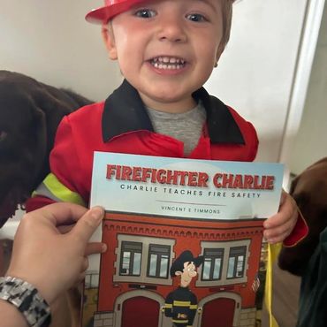 Toddler in firefighter costume holding safety book