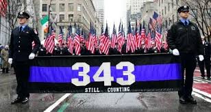Uniformed officers holding 343 memorial banner amid flags